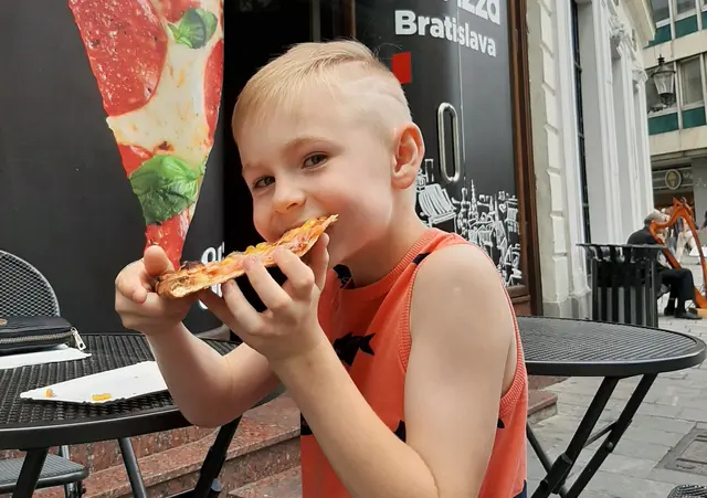 Chlapec je kúsok pizze pri stolíku na terase pred prevádzkou I Love Pizza