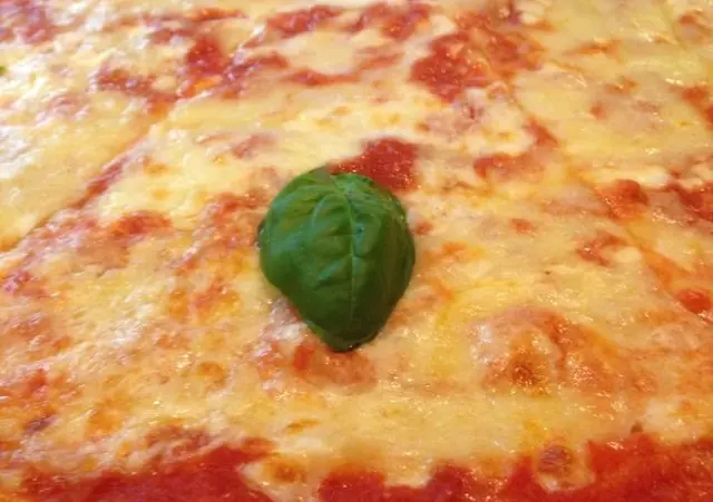 Detail pizze Margherita s paradajkovou omáčkou, mozzarellou a lístkami bazalky