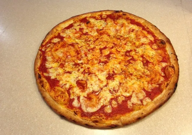 Celá pizza Margherita s drvenými paradajkami, roztopenou mozzarellou a bylinkami