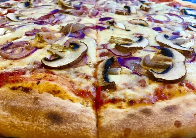 Detail pizze so šampiňónmi, červenou cibuľou, mozzarellou a opečeným okrajom