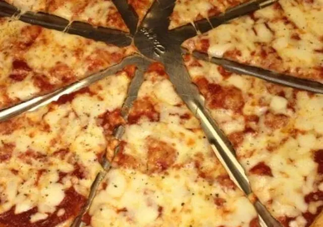 Syrová pizza s paradajkovou omáčkou nakrájaná na osem kúskov na kovovom podnose